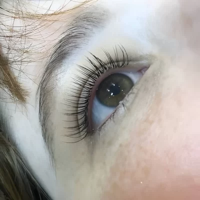 pale faced female with classic eyelash extensions being applied