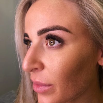 Confident woman with blonde hair showcasing Russian volume eyelash extensions.